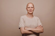 Warm-toned waist up portrait of confident bald woman looking at camera while posing against minimal beige background in studio, alopecia and cancer awareness, copy space
