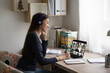 © fizkes - Smiling Caucasian female employee in headphones sit at desk at home talk on video call with colleagues, young woman have online webcam conversation virtual event with diverse multiethnic coworkers