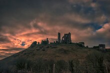 The Sun Rises Behind The Ruins Of Corfe Castle In Dorset, UK
