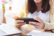© Nutlegal - Asian woman playing online game application or chatting text messaging with friend by using smart phone at house during break time of working at home that make her get fun. addicted online game, phone