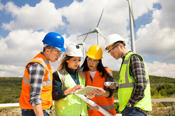 Young workers looking and checking wind turbines at field