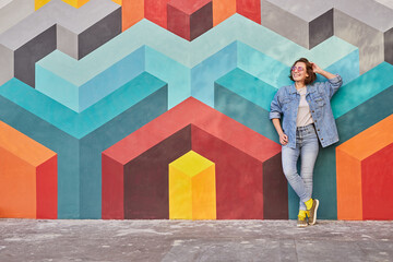 Wall Mural - Young woman leaning on colorful wall