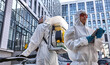 © Roman - hard-working professional confident disinfectors in New York city at work, two workers in hazard suits use tablet and sprayers for cleaning contaminated area