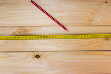 The man measures the Board with a tape measure and makes marks with a pencil.