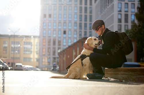 handsome blind guy have rest with golden retriever in the city, young male sit with guide dog, love him, dog assist him while walking