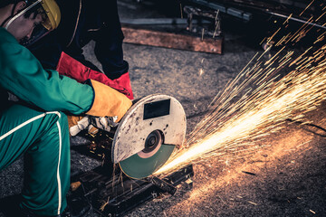 Wall Mural - Professional mechanic man is cutting steel metal with rotating carbon blade cutter. Steel industry and workshop concept.