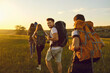 © Studio Romantic - Hike. Hiking. Tourism.A group of tourists with backpacks are walking along the hill at sunset in nature in summer.