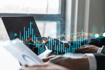 Two business people working together on stock market strategy. Try to analyze forex behavior. Financial graph hologram. Double exposure.