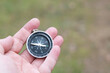 © yarbeer - Old classic navigation compass in hand on natural background as symbol of tourism with compass, travel with compass and outdoor activities with compass