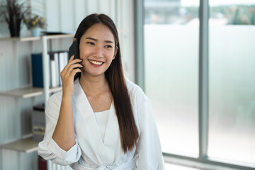 young asian woman talking on mobile phone with happily.