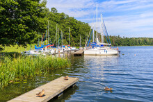 Ducks On Wooden Lake Pier And Sailboats Mooring In Small Marina Janus Near Ruciane Nida Town, Mazury Lake District, Poland