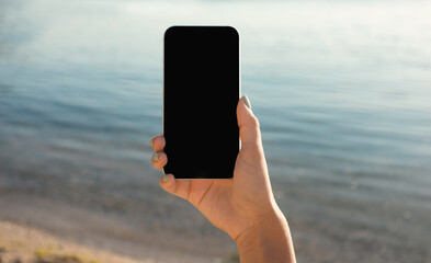 Hand Holding Cellphone With Blank Screen Against Sea Beach Outdoor