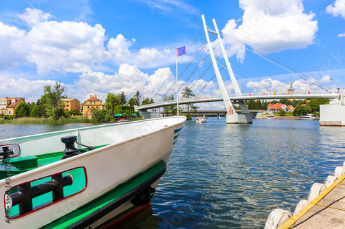 Boat mooring in Mikolajki port with bridge in background on sunny summer day,...
