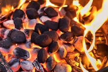 Top View Of Hot Flaming Charcoal Briquettes Glowing In The BBQ Grill Pit. Grill Briquettes That Are Burning And Waiting To Be Glowed For Grilling.