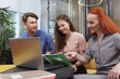 © Ihor - Two female entrepreneurs talking to male colleague while using laptop at workplace