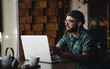 © mykolastock - Thoughtful young handsome bearded hipster male student with laptop sitting in cafe listening to audio book and looking into the window.