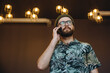 © mykolastock - Confident stylish bearded male hipster talking on phone