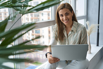 Wall Mural - Smiling pretty woman with laptop at home