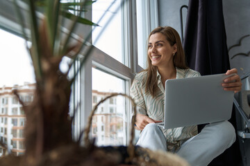 Wall Mural - Happy woman with laptop in city apartment