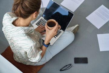 Wall Mural - Woman with hot drink using laptop at home