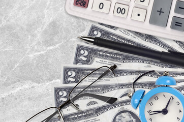 2 US dollars bills and calculator with glasses and pen. Business loan or tax payment season concept. Time to pay taxes