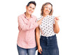 © Krakenimages.com - Couple of women wearing casual clothes smiling and looking at the camera pointing with two hands and fingers to the side.