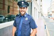 Young handsome hispanic policeman wearing police uniform smiling happy Standing with smile on face at town street.