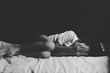 © AungMyo - Sad little girl covers face with both hands lying in bed room. black and white image