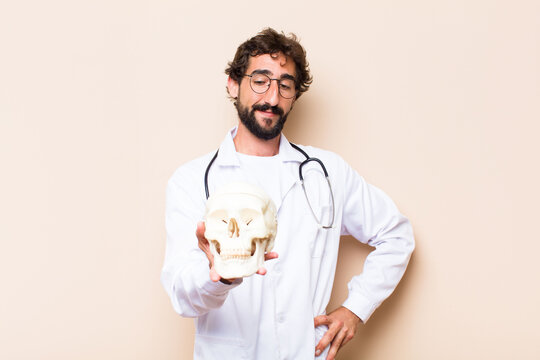 young physician man and a human skull model.