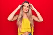 © Krakenimages.com - Young beautiful blonde woman wearing yellow t-shirt standing over isolated red background with hand on head, headache because stress. Suffering migraine.