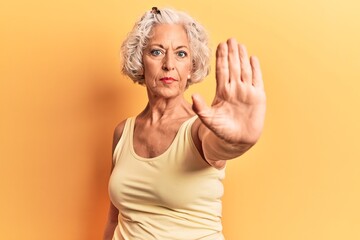 Senior grey-haired woman wearing casual clothes doing stop sing with palm of the hand. warning expression with negative and serious gesture on the face.