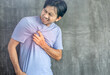 © anut21ng Stock - Young asian man with chest pain on a gray background with copy space, Problems and health care concepts