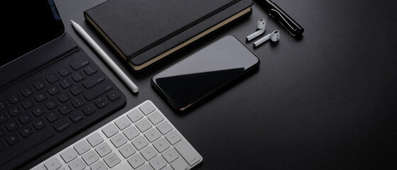 digital devices with smartphone, tablet, keyboard, stationery, accessories and copy space on dark ta