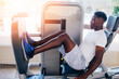 © twinsterphoto - Back view of African American man doing exercise on leg press during fitness training in modern gym.