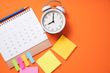 Close Up Of Alarm Clock And Calendar On The Orange Table Background, Planning For Business Meeting Or Travel Planning Concept