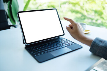 Mockup image of a woman using and pointing finger at tablet pc with blank desktop white screen as a computer pc