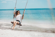 Young Beautiful Curly Woman Girl Swinging And Having Fun On A Swing On A Tropical Beach Vacation And Travel Concept.
