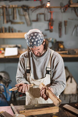 Wall Mural - Male carpenter working on old wood in a retro vintage workshop.