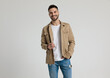 happy young casual guy in jacket holding hand in pocket