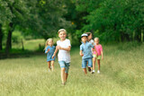 Fototapeta Las - Kids, children running on meadow in summer's sunlight. Look happy, cheerful with sincere bright emotions. Cute caucasian boys and girls. Concept of childhood, happiness, movement, family and summer.