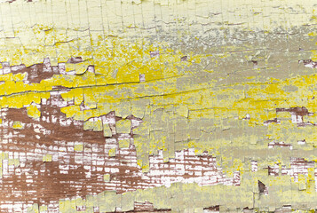 Textured surface of a old painted wooden board with a peeling and cracked layer of yellow and white paint closeup. The aged natural wood backdrop, vintage door or rustic fence. Retro background.