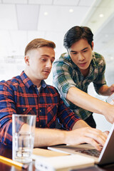 young multi-ethnic software developers discussing programming code on laptop screen