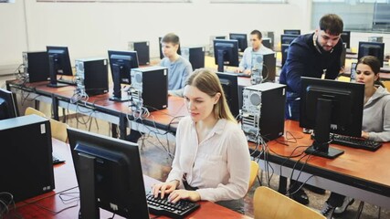Male trainer helping young female student in computer class. High quality FullHD footage