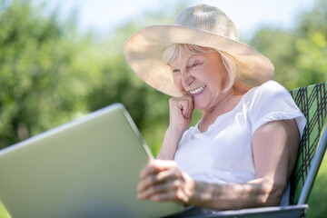 Concentrated elderly woman texting her friends via the laptop