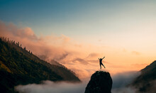 Silhouette Of A Man Jump And Rises Arms Up On A Peak. The Happiness And Excitement Of Beeing Successful.
