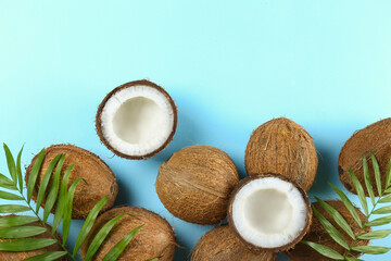 Wall Mural - Top view shot of coconuts, whole and cracked on halves on paper textured background with a lot of copy space for text. Background with raw fruit of tropical palm. Flat lay.