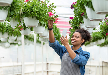 Wall Mural - Modern technology in gardening business. Smiling girl with smart watch makes photo on smartphone