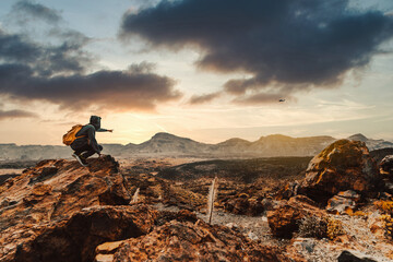 Wall Mural - Success hiker hiking on sunrise mountain peak pointing to the sky.