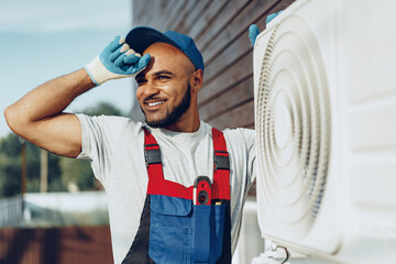 Wall Mural - Young black man repairman checking an outside air conditioner unit