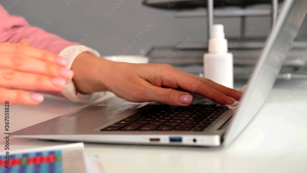 Hands of a woman who is using a wipe to clean her laptop - obrazy, fototapety, plakaty 